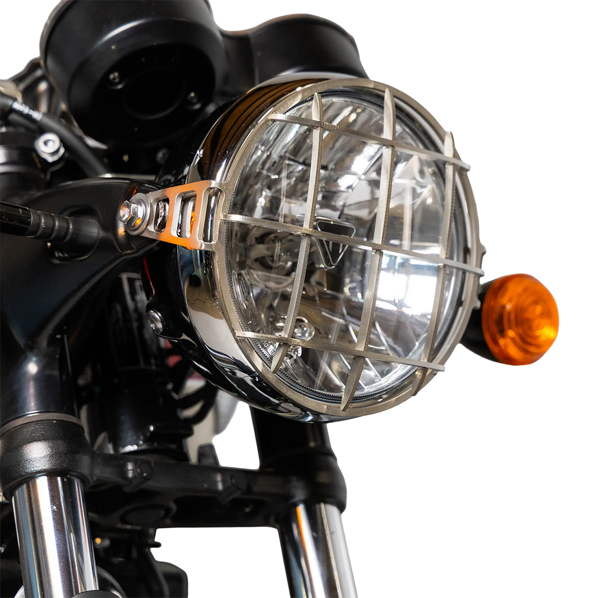 Grille de phare inox brossee montee sur le phare d’origine d’une Triumph Bonneville, gros plan de face avec clignotant - FCR Accessoires